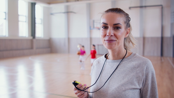 A PE female teacher standing indoors in gym class, physical education concept