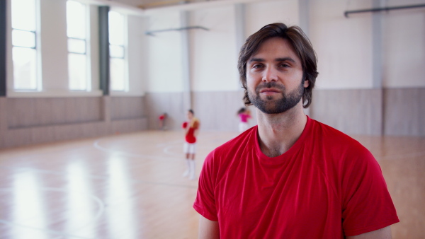 A PE teacher standing indoors in gym class, physical education concept