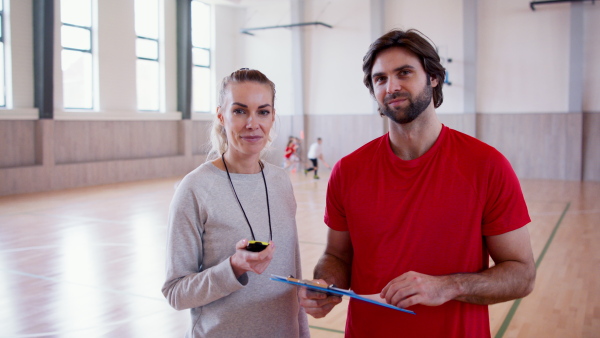 A PE teacher standing indoors in gym class, physical education concept