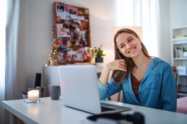 Beautiful happy young girl with laptop sitting and smiling, online dating and chatting concept.