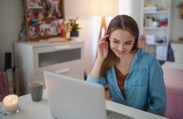 Beautiful happy young girl with laptop sitting and smiling, online dating and chatting concept.