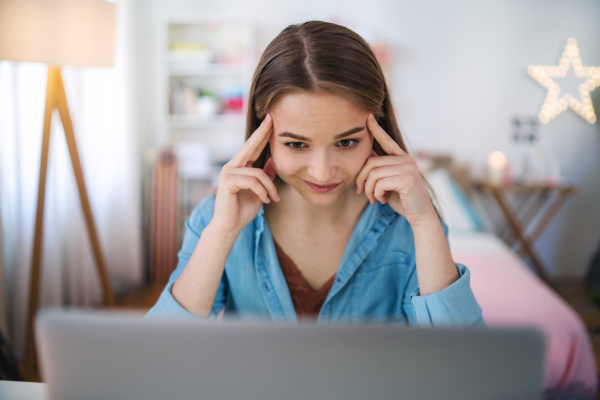 Beautiful happy young girl with laptop sitting and smiling, online dating and chatting concept.