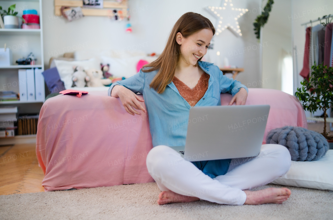 Beautiful happy young girl with laptop sitting and smiling, online dating and chatting concept.