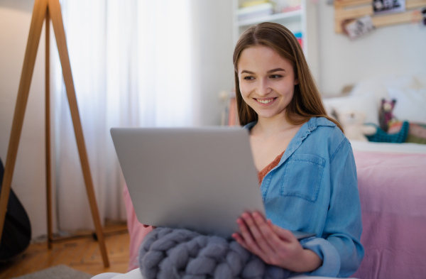 Beautiful happy young girl with laptop sitting and smiling, online dating and chatting concept.