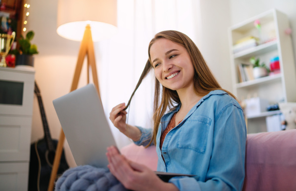 Beautiful happy young girl with laptop sitting and smiling, online dating and chatting concept.