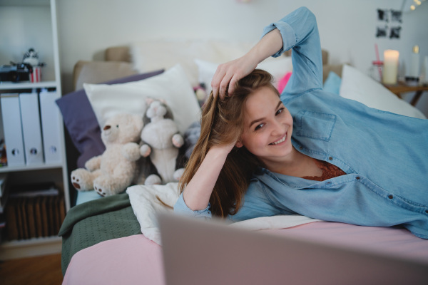 Beautiful happy young girl with laptop sitting and smiling, online dating and chatting concept.