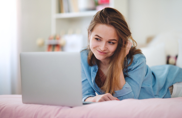 Beautiful happy young girl with laptop sitting and smiling, online dating and chatting concept.