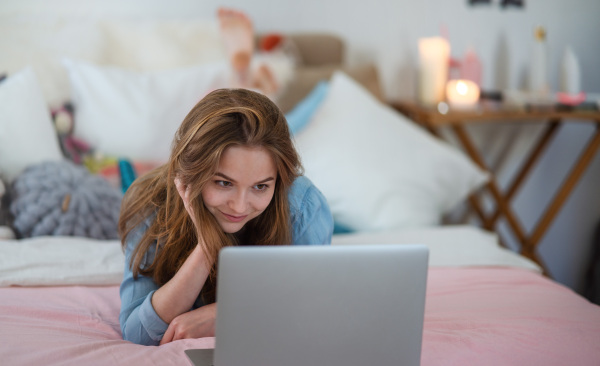 Beautiful happy young girl with laptop sitting and smiling, online dating and chatting concept.