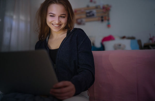 Beautiful happy young girl with laptop sitting and smiling, online dating and chatting concept.