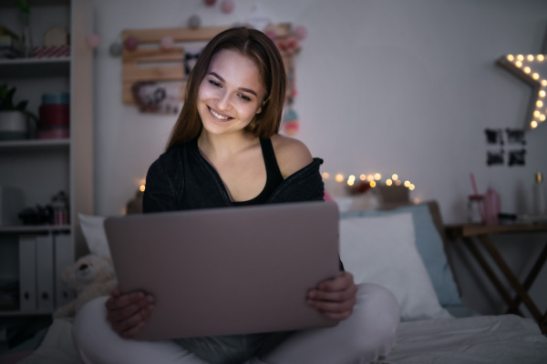 Beautiful happy young girl with laptop sitting and smiling, online dating and chatting concept.