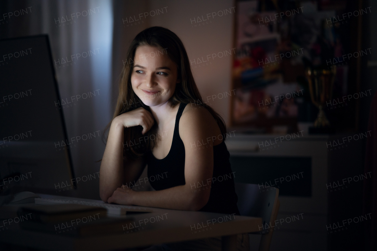 Beautiful happy young girl with laptop at night smiling, online dating concept.