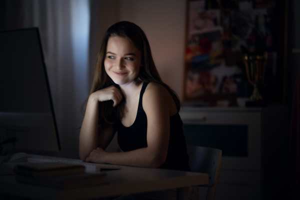 Beautiful happy young girl with laptop at night smiling, online dating concept.