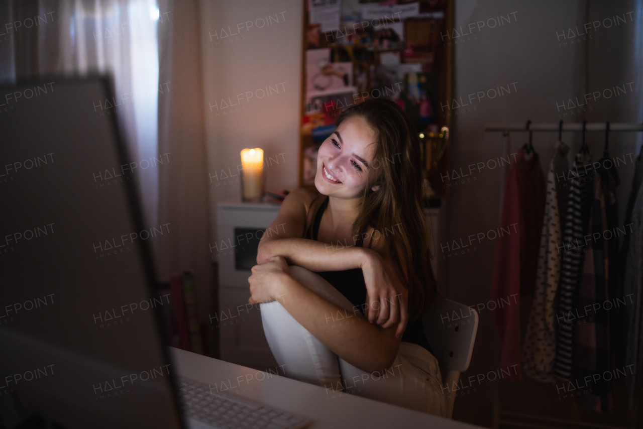 Beautiful happy young girl with computer at night smiling, online dating concept.