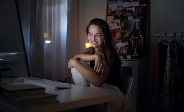 Beautiful happy young girl with laptop at night smiling, online dating concept.