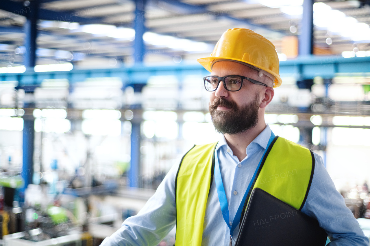 Technician or engineer with helmet standing in industrial factory. Copy space.