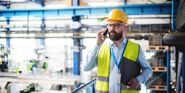 Man technician or engineer with protective mask and telephone working in industrial factory.