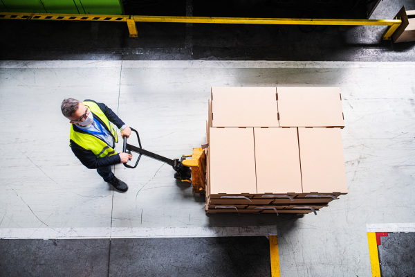 Aerial view of man worker or technician with protective mask working in industrial factory or warehouse.