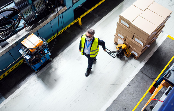 Aerial view of man worker or technician with protective mask working in industrial factory or warehouse.