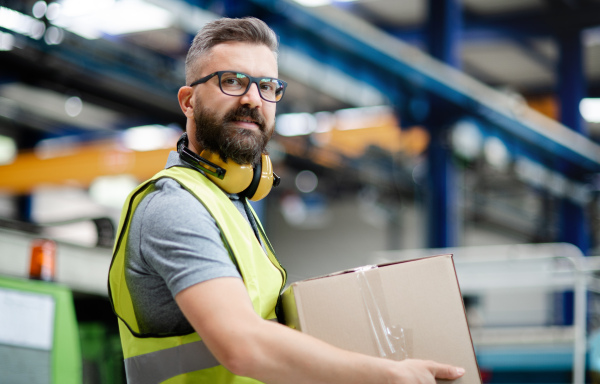 Portrait of man worker working in industrial factory or warehouse.