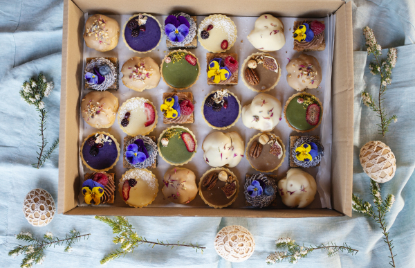 A top view of selection of colorful and delicious cake desserts in box on table.