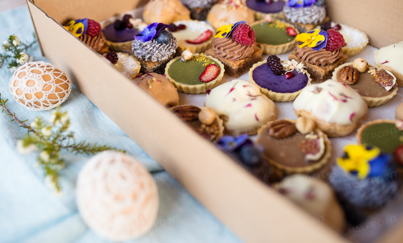 A selection of colorful and delicious cake desserts in box on table.