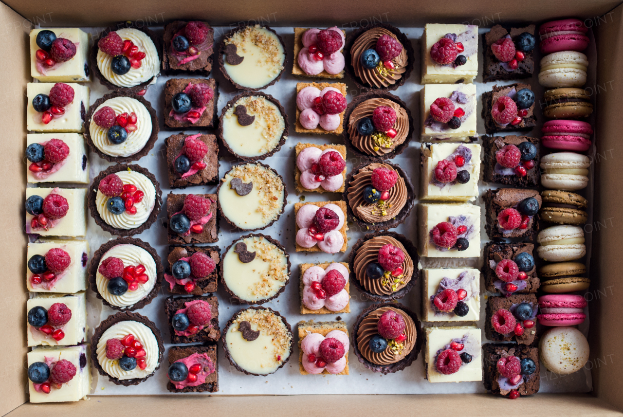 A top view of selection of colorful and delicious cake desserts in box.