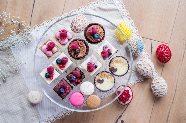 A top view of selection of colorful and delicious cake desserts on tray on table.