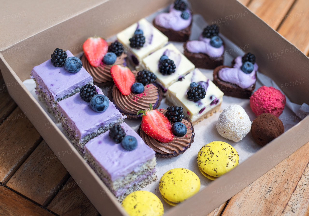 A selection of colorful and delicious cake desserts in box on table.