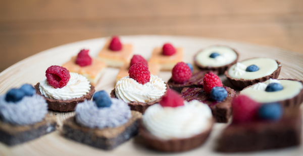 A selection of colorful and delicious cake desserts on tray on table.