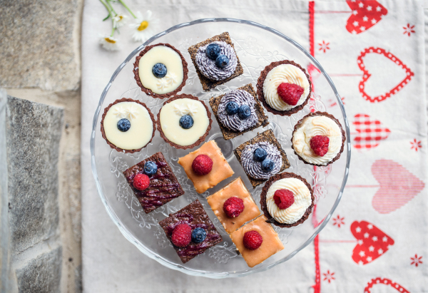 A top view of selection of colorful and delicious cake desserts on tray on table.