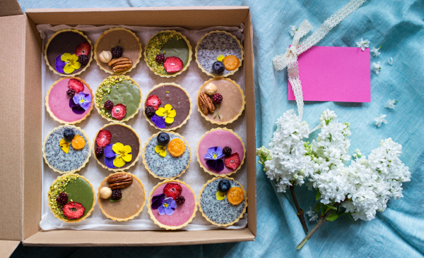 A selection of colorful and delicious cake desserts in box on table, top view.