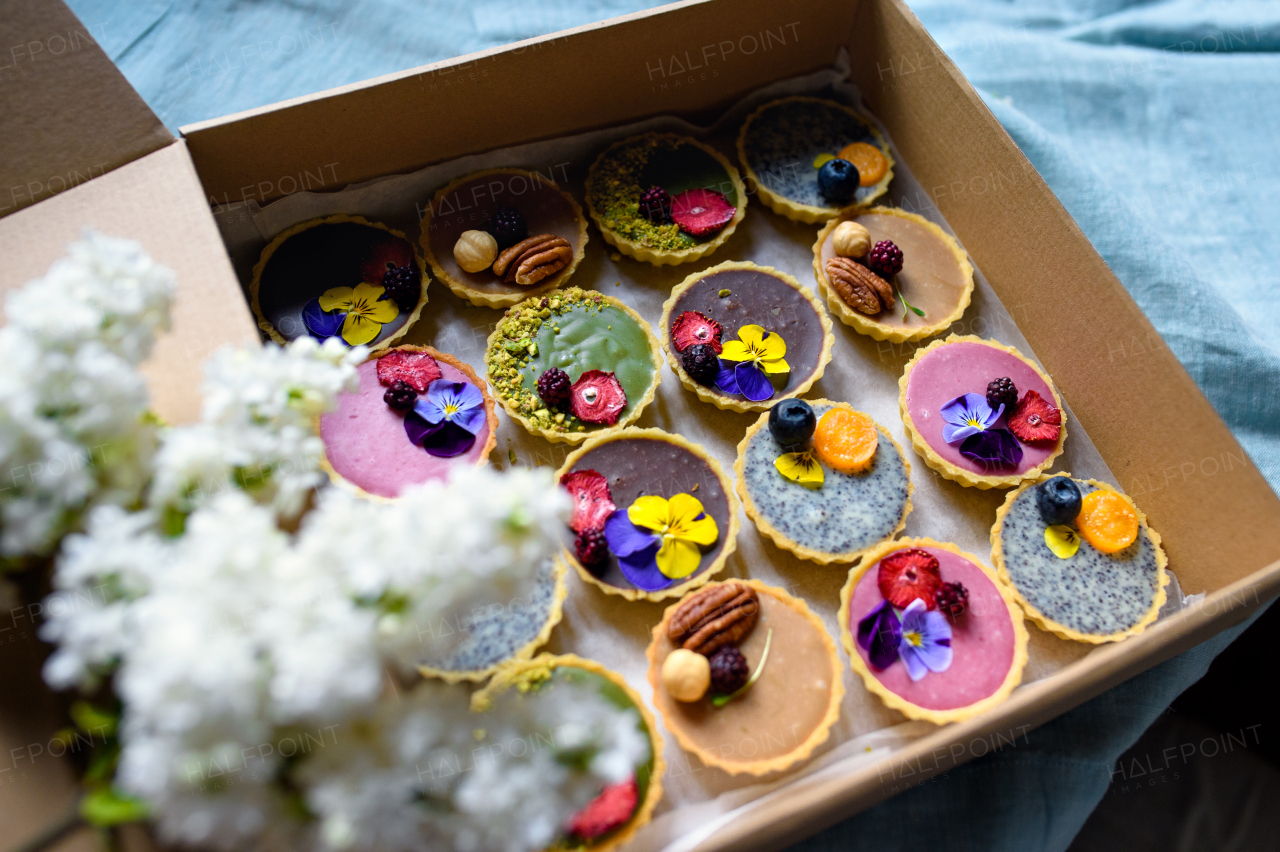 A selection of colorful and delicious cake desserts in box on table, top view.