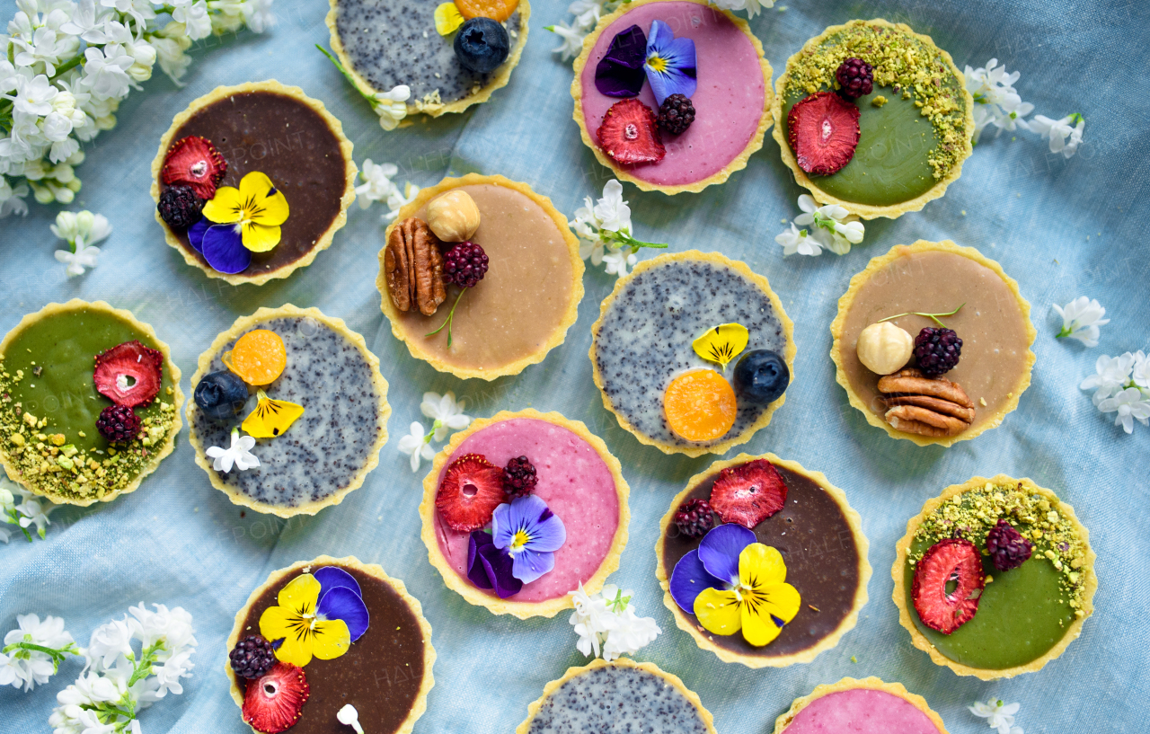 A selection of colorful and delicious cake desserts in box on table, top view.