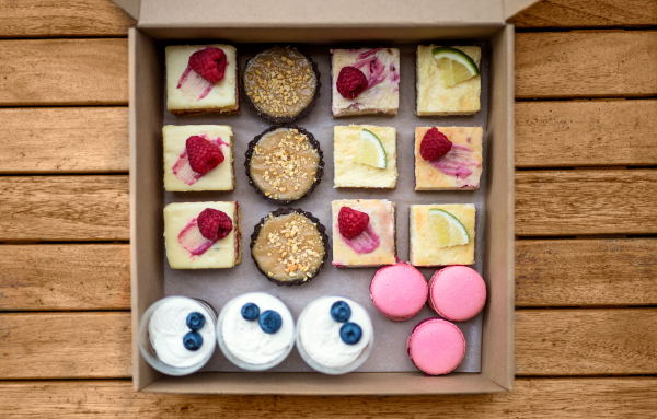 A selection of colorful and delicious cake desserts in box on table, top view.