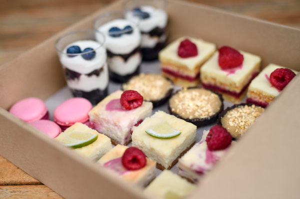 A selection of colorful and delicious cake desserts in box on table.