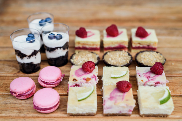 Selection of colorful and delicious cake desserts on a rusty wooden table.