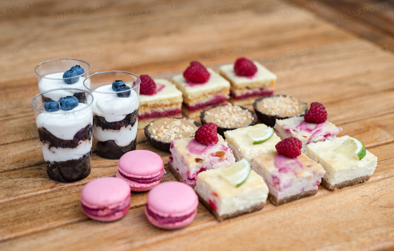 Selection of colorful and delicious cake desserts on a rusty wooden table.