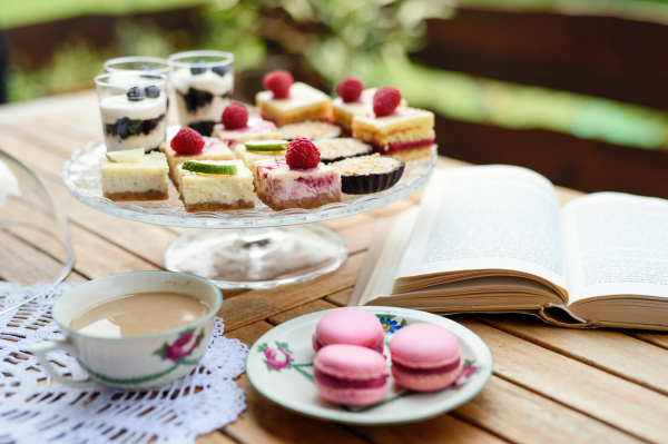 A cup of coffee and desserts on table outdoors on terrace.