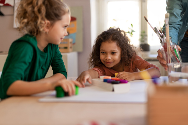 Happy little girls preparing for an art class indoors at school