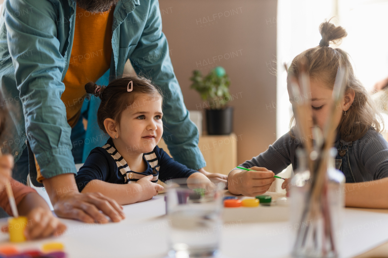 A group of little kids working on project with teacher during creative art and craft class indoors at school.