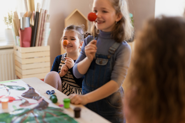 Two litlle girlss working on a project, smiling and having fun during creative art and craft class at school.