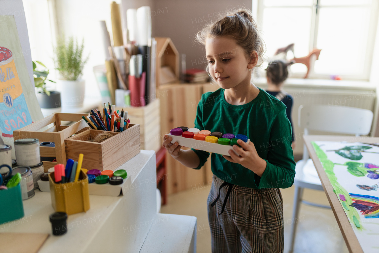 A happy little girl preparing for art and craft class indoors at school