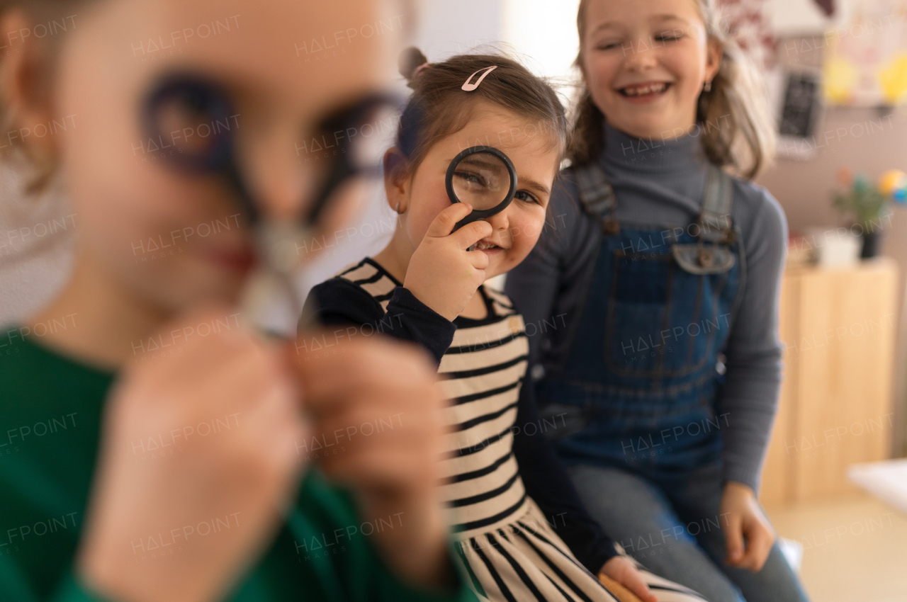 A happy little girl with her friend preparing for art class indoors at school