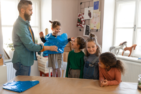 Group of little kids with teacher working are preparing for pottery and art class at school.