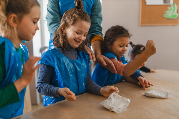 A group of little kids working with pottery clay during creative art and craft class at school.