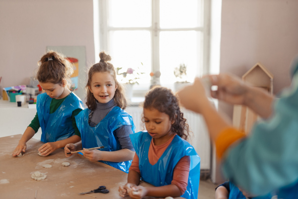 A group of little kids working with pottery clay during creative art and craft class at school.