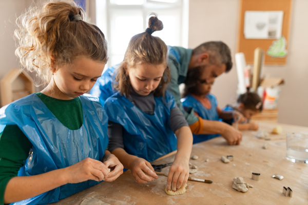 A group of little kids with teacher working with pottery clay during creative art and craft class at school.