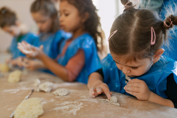 A group of little kids working with pottery clay during creative art and craft class at school.