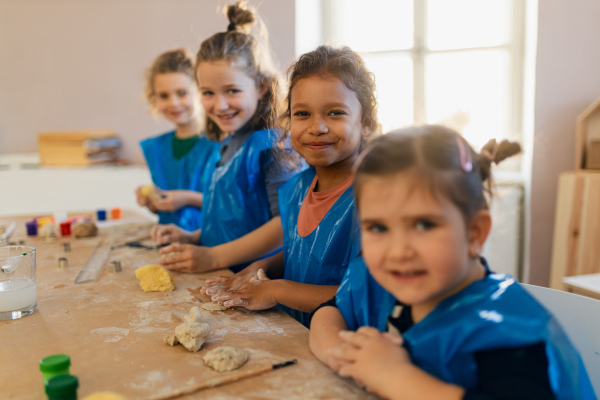 A group of little kids working with pottery clay during creative art and craft class at school.