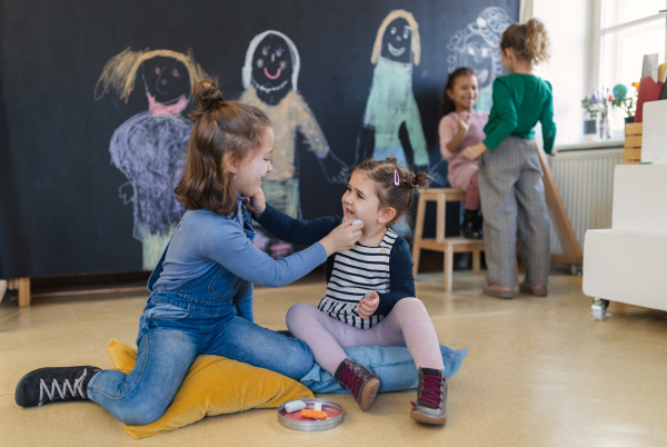 A rear view of group of little girls drawing with chalks on blackboard wall